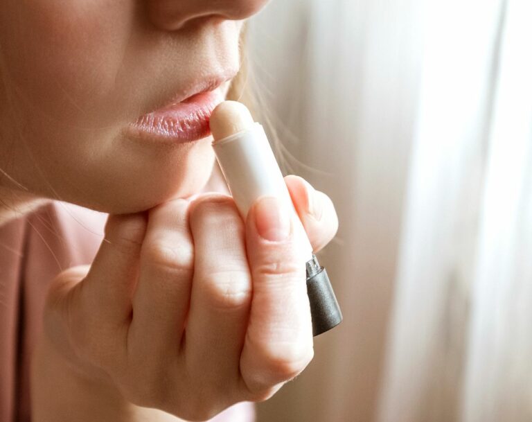 Nainen levittää huulirasvaa huulilleen. Vinkkejä siihen, voiko huulirasvasta tulla riippuvaiseksi.