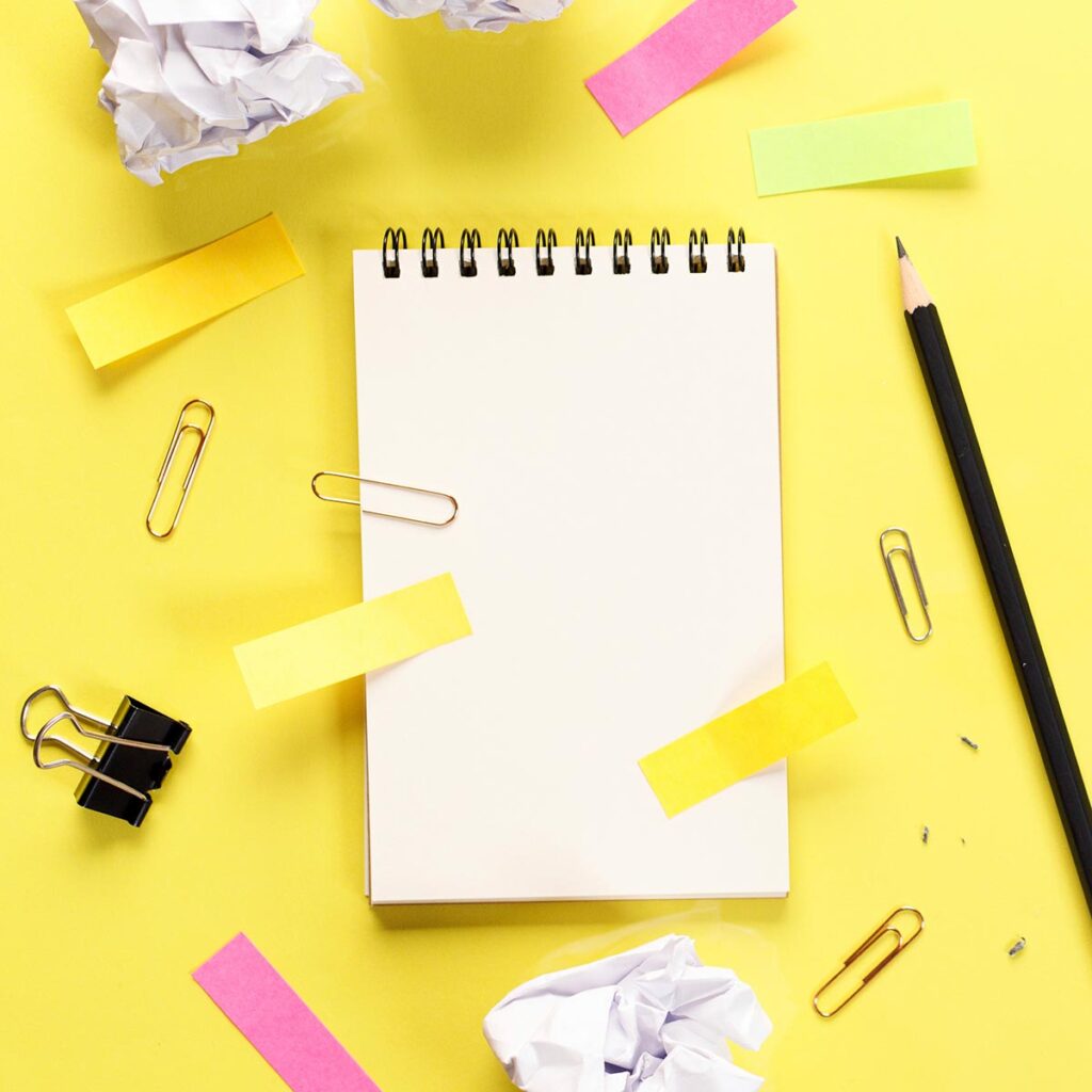 Muistikirja ja kynä keltaisella pohjalla