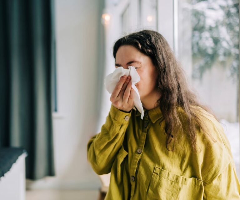 Poskiontelontulehdus vaivaa. Kuvassa nainen niistää nenää.